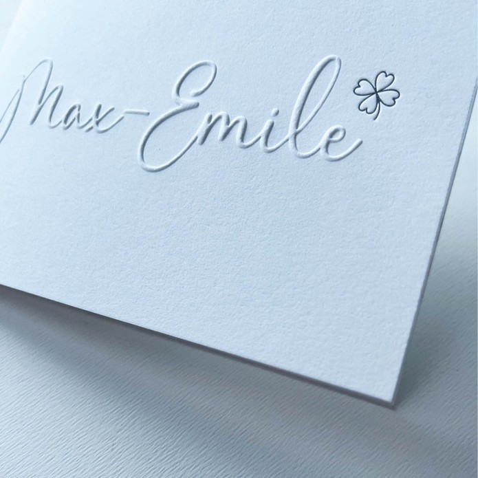 Minimalistisch geboortekaartje met reliëfdruk en zilveren klavertje