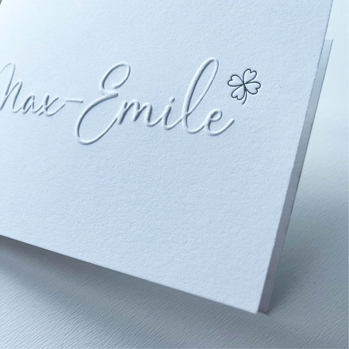 Minimalistisch geboortekaartje met reliëfdruk en zilveren klavertje