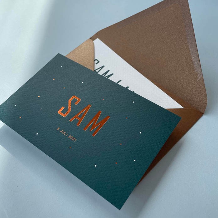 Petrol geboortekaartje met koper stipjes op de voorkant